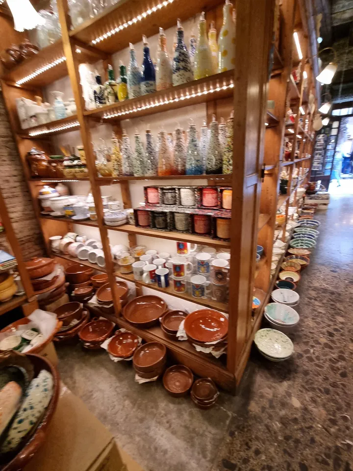 Prestatges de fusta amb ampolles de vidre, pots i cassoles de fang