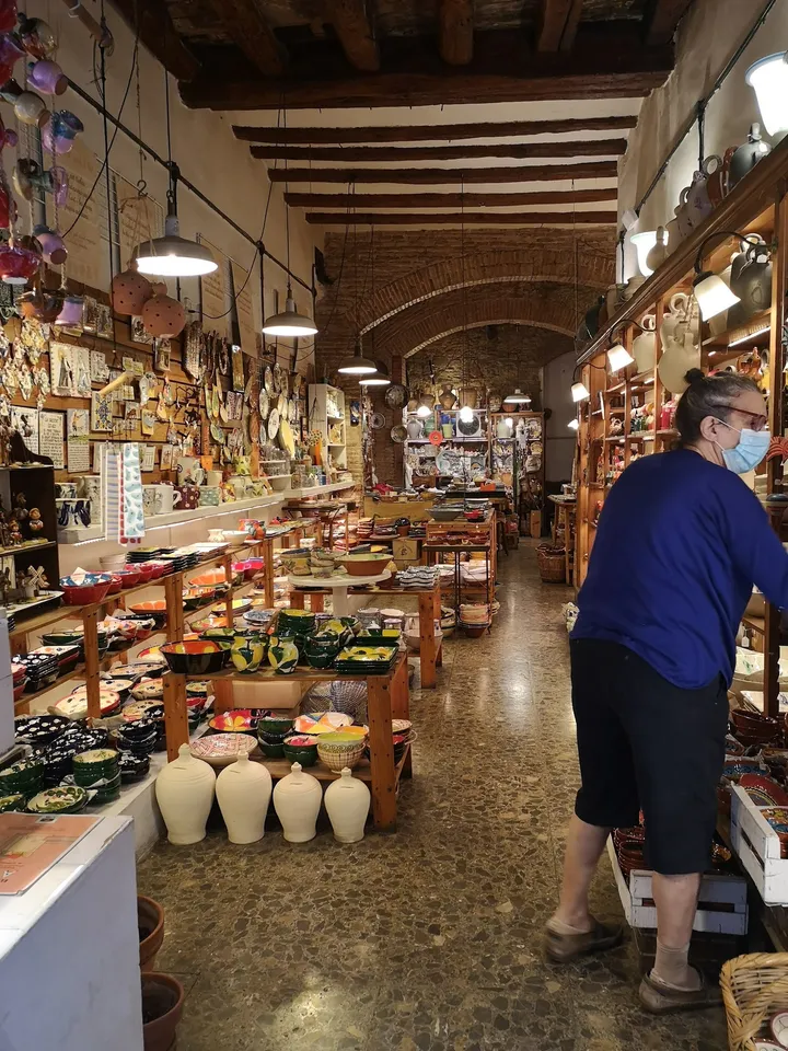 L'interior allargat de la botiga, amb bigues de fusta, arcs de maó i taules plenes de ceràmica